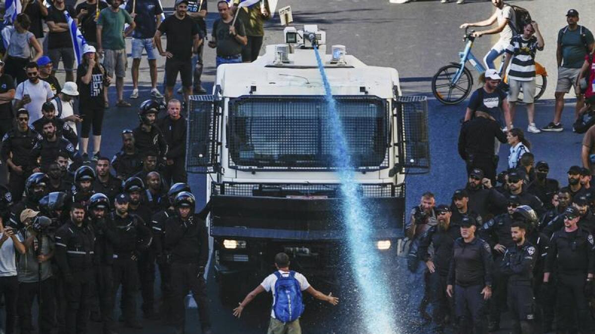A person stands in front of an Israeli police water cannon