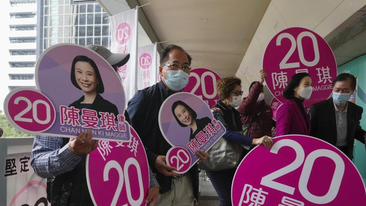 Supporters hold cutouts of a pro-Beijing candidate