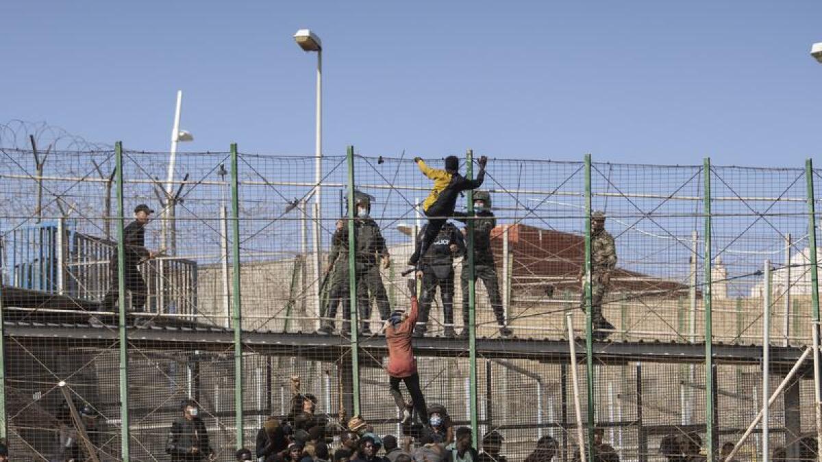 Migrants climb fences separating Spanish enclave Melilla from Morocco.