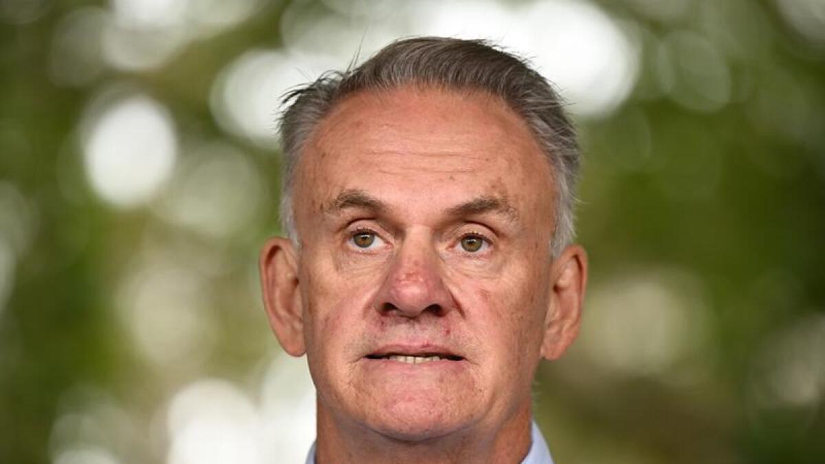Mark Latham speaks in front of trees.