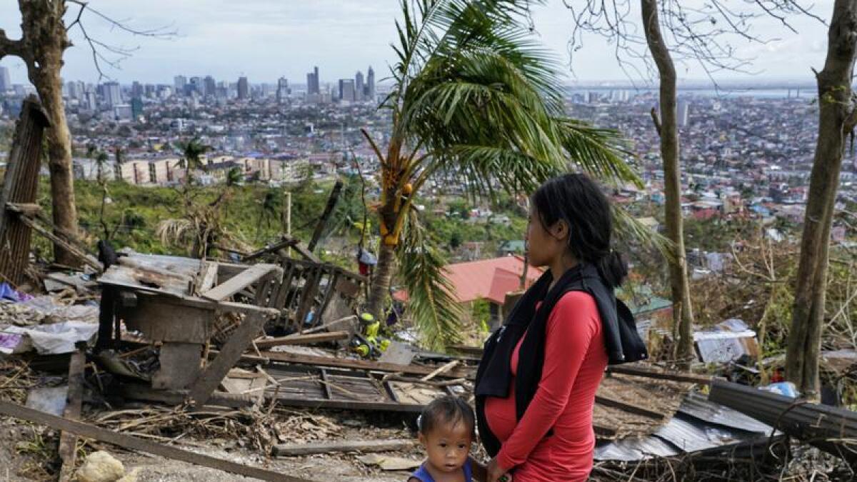 Woman and son look at their damaged house in Cebu city, Philippines.