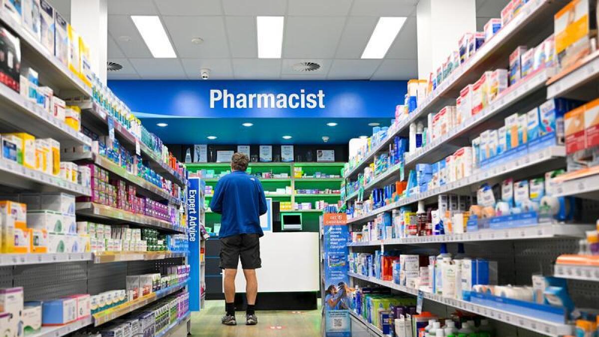 A man waits at a pharmacy counter.