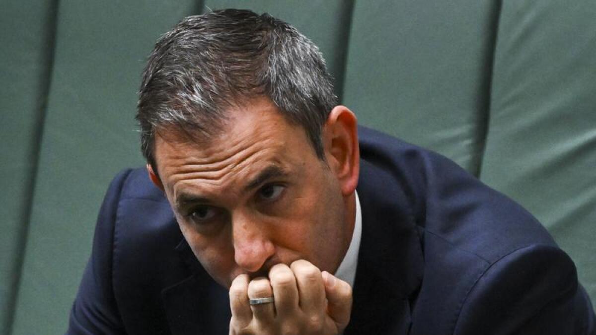 Jim Chalmers sits in parliament with his hand across his mouth.