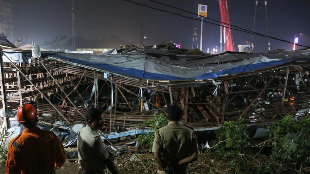 Police and responders view a collapsed billboard in Mumbai