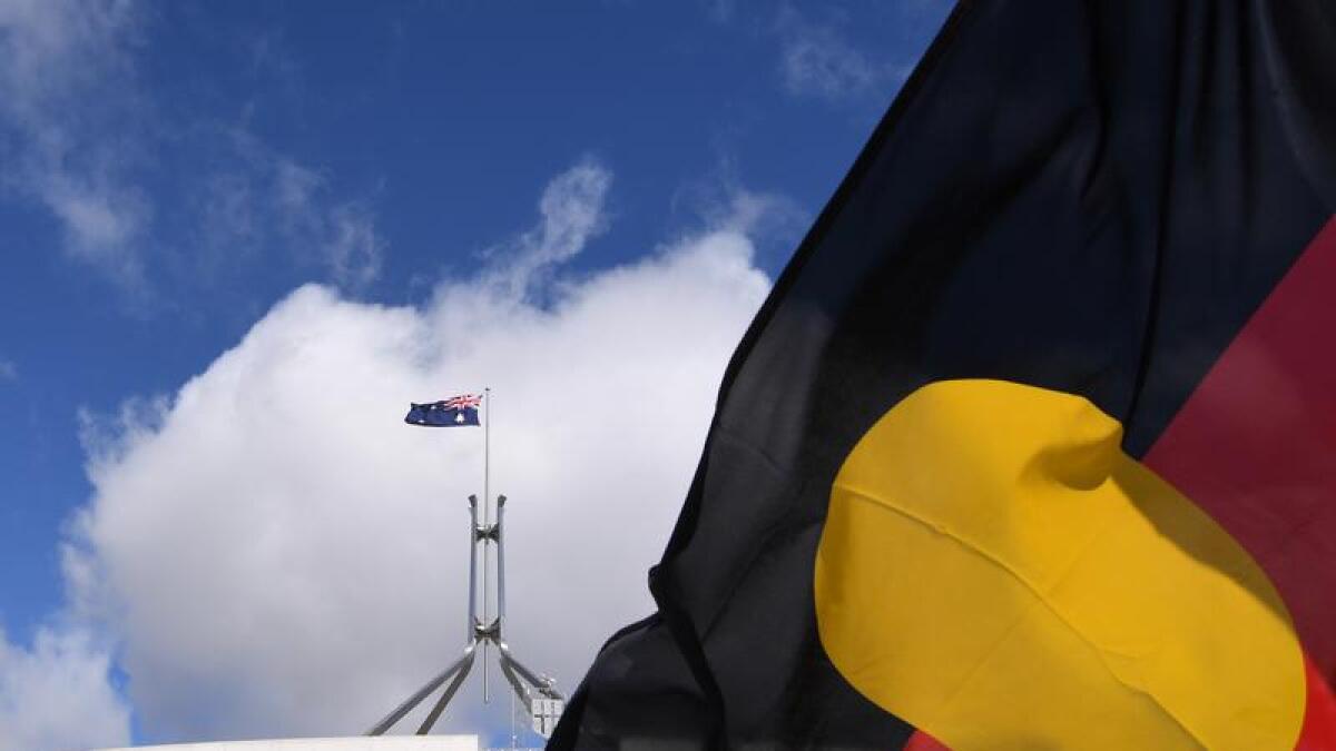Australian Parliament House is seen through an Aboriginal flag