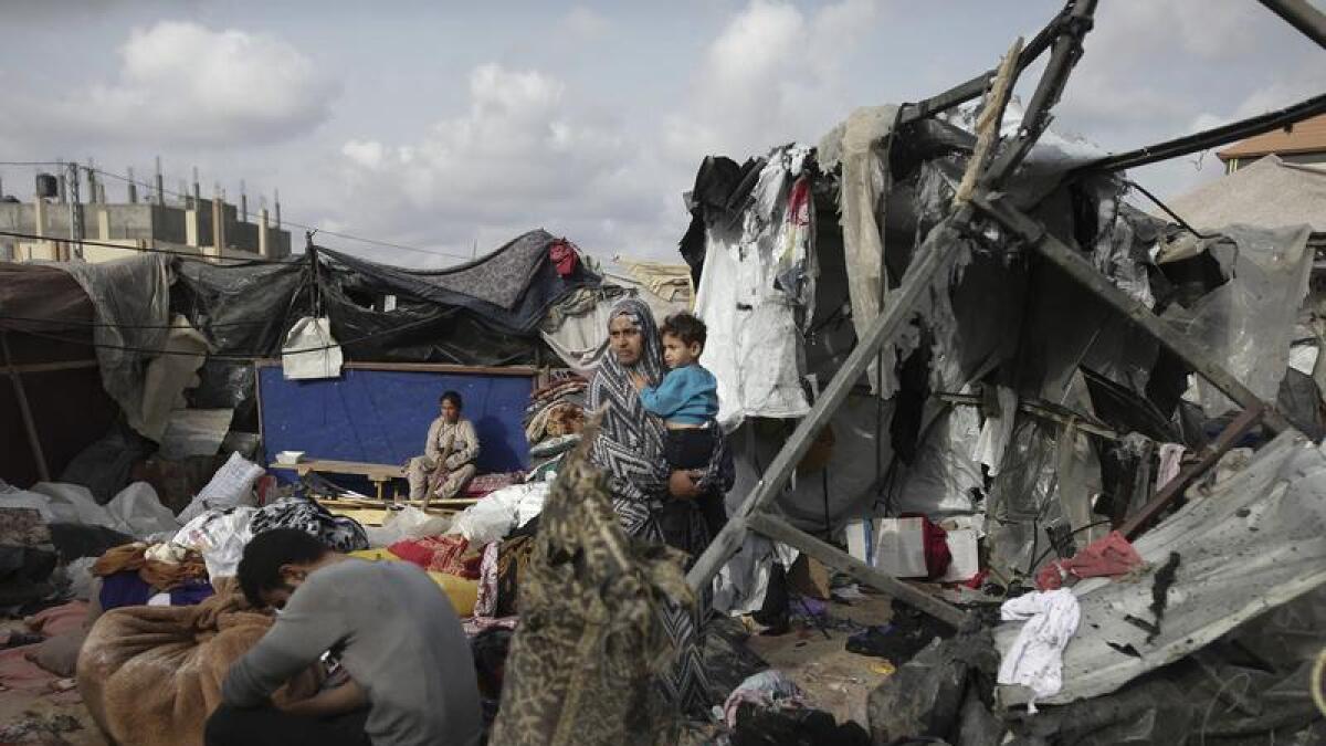 People in Gaza sit in the ruins of tents in which they were living.