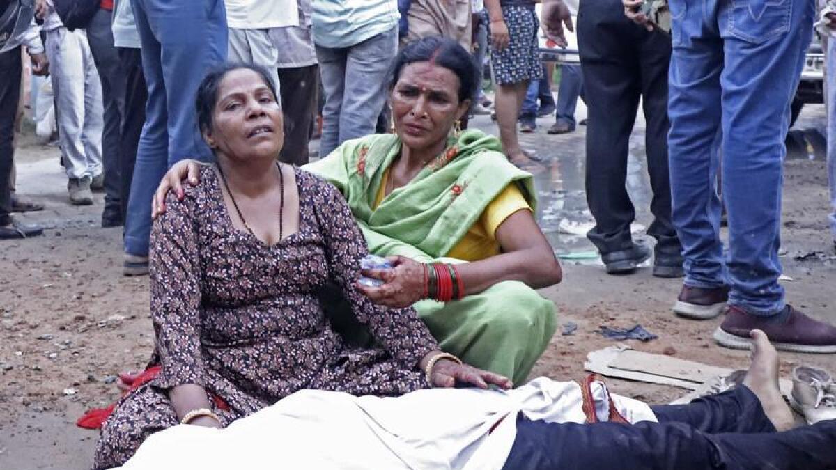 Women mourn next to the body of a relative in India