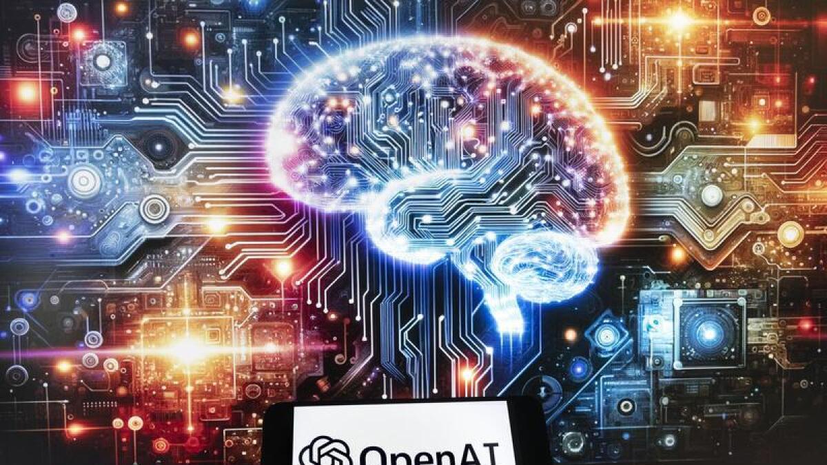 The OpenAI logo on a mobile phone in front of a ;aptop.