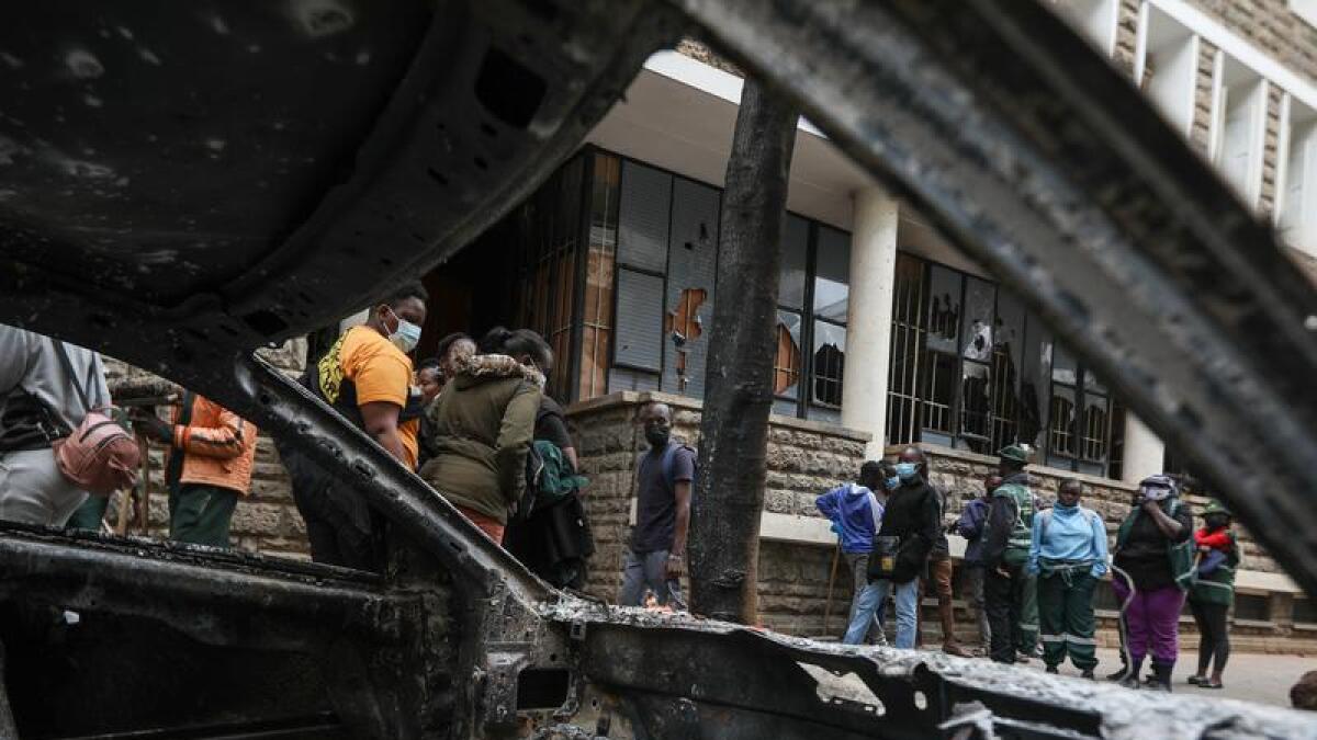 People walk past a car torched in Nairobi