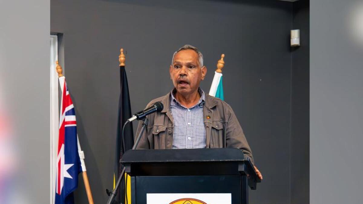 Palm Island Aboriginal Shire mayor Alf Lacey stands at a podium.
