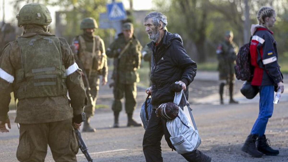 Russian servicemen control the evacuation of civilians from Azovstal.