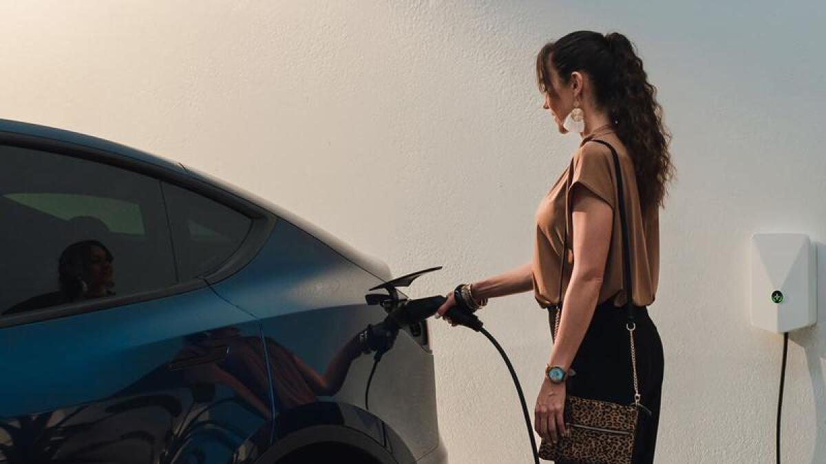 A woman charging an electric vehicle