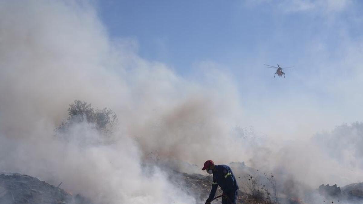 A firefighter tries to extinguish a fire burning in Greece