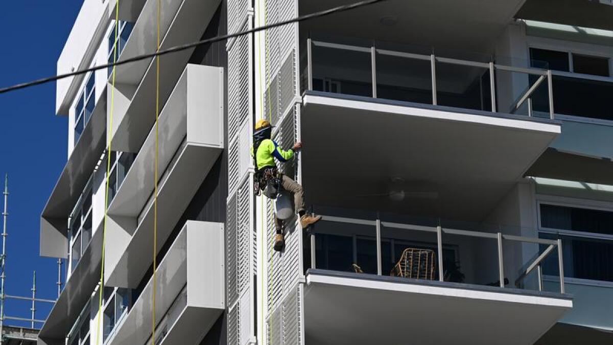 A construction worker is seen working on the side of a new apartment