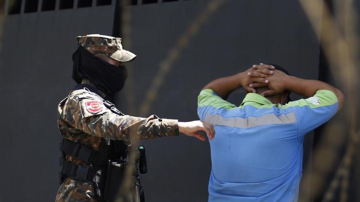 A soldier arrests a man in El Salvador.