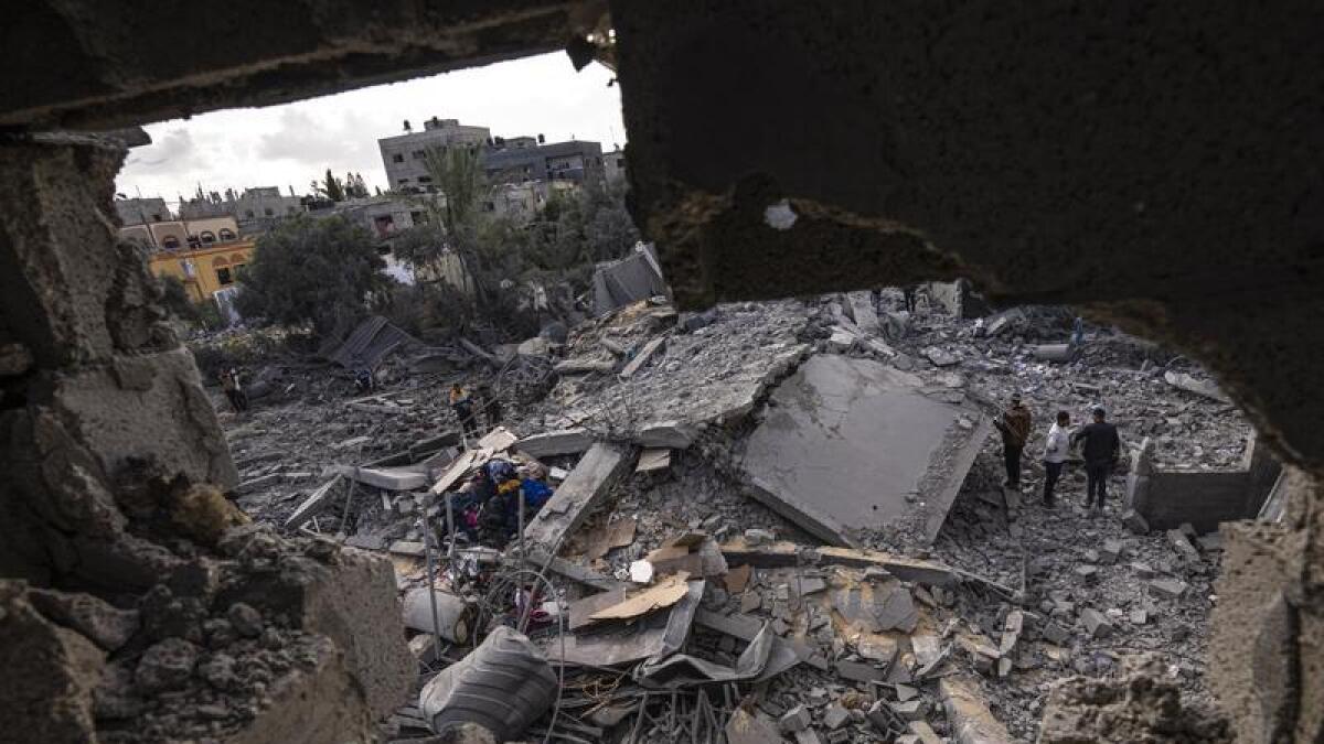 Palestinians inspect the rubble at the site of an air strike