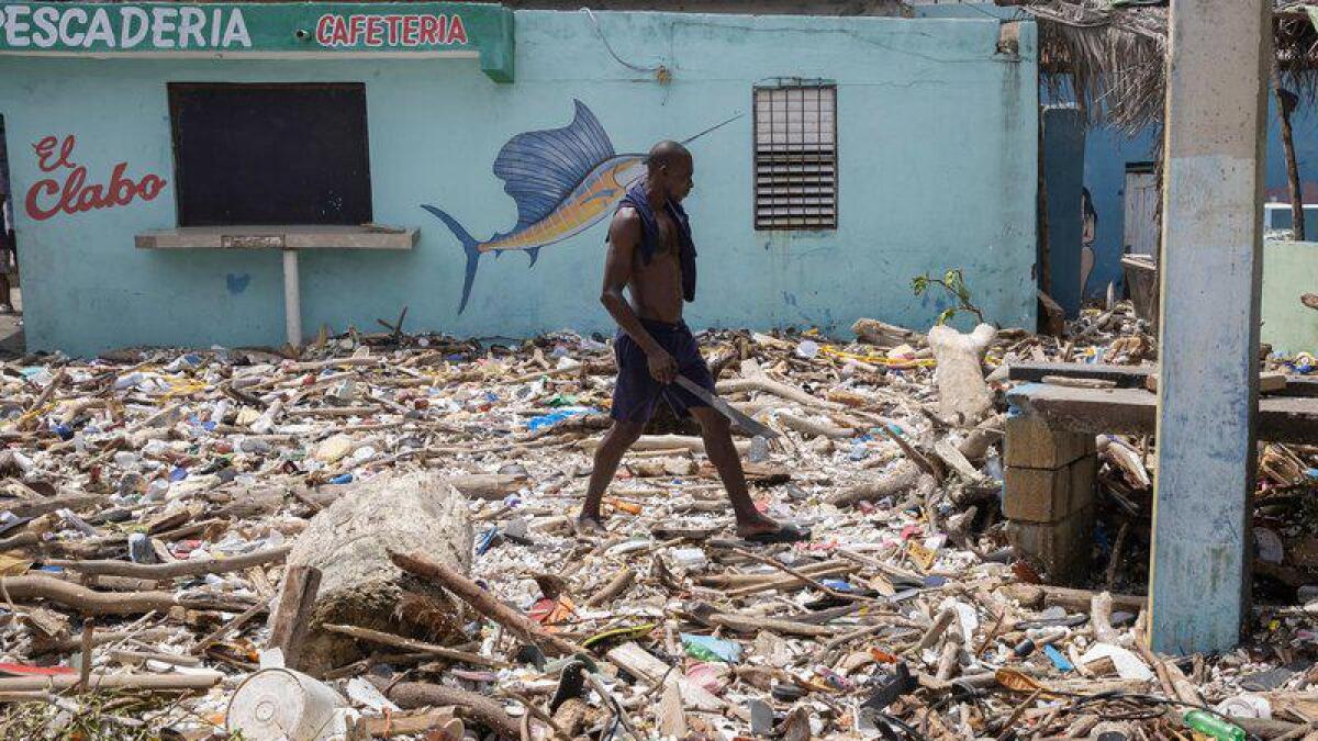 A man walks on a beach covered with garbage in the Dominican Republic