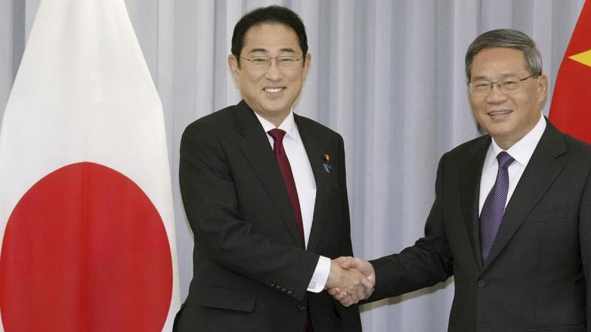 Japan's Fumio Kishida shakes hands with Chinese Premier Li Qiang
