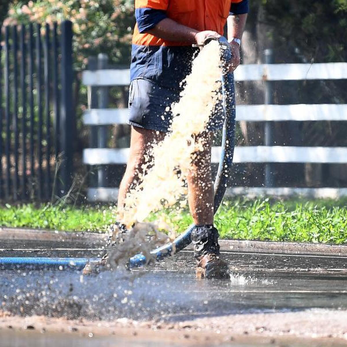 Generic photo of council worker washing mud off a road