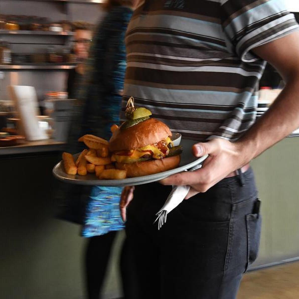A waiter carries a burger.