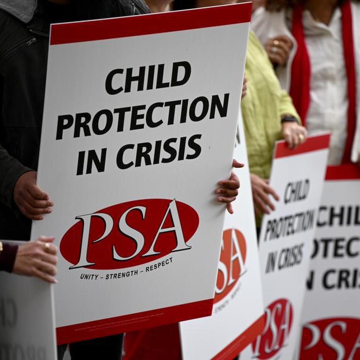 Child protection workers hold placards prior to a press conference
