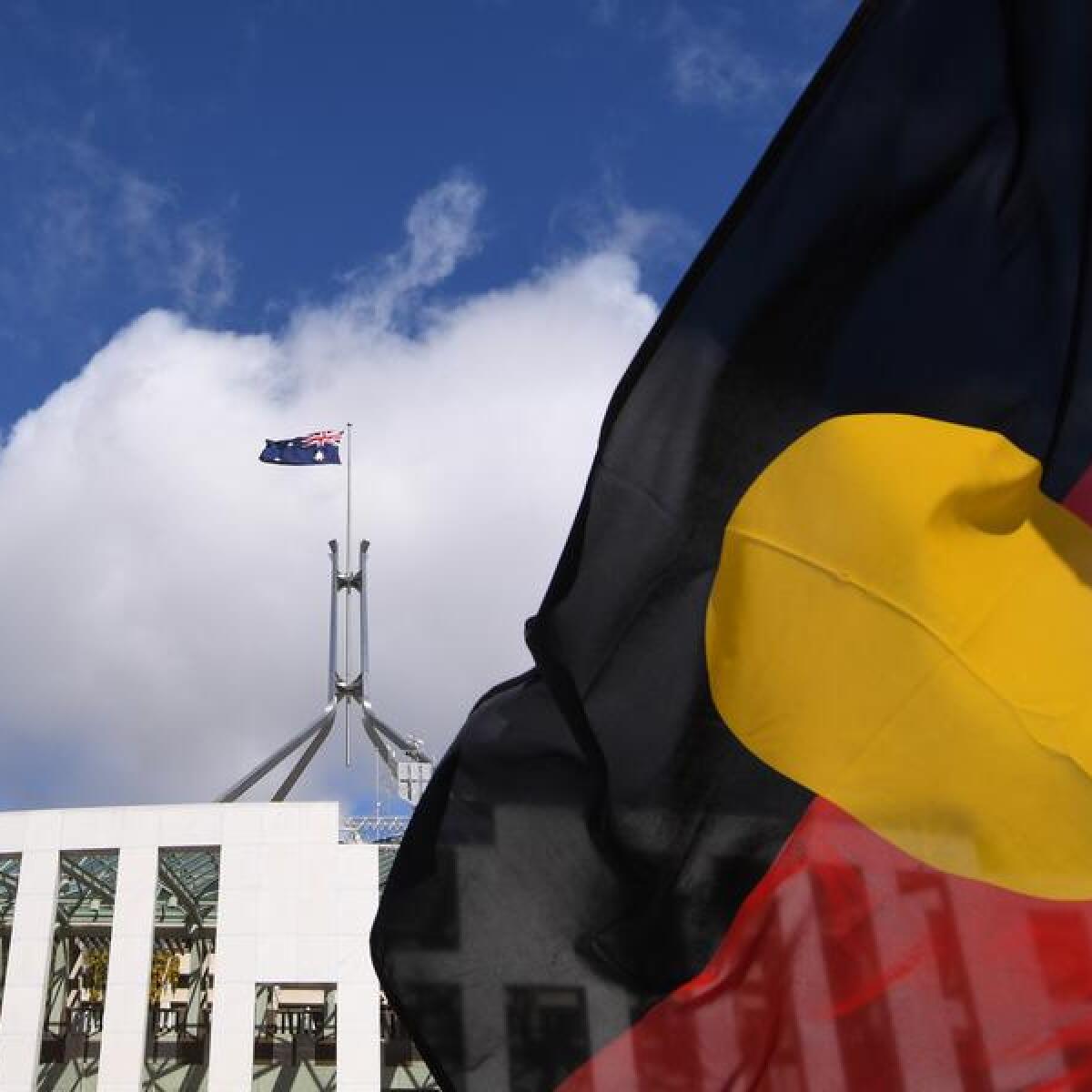 Australian Parliament House is seen through an Aboriginal flag