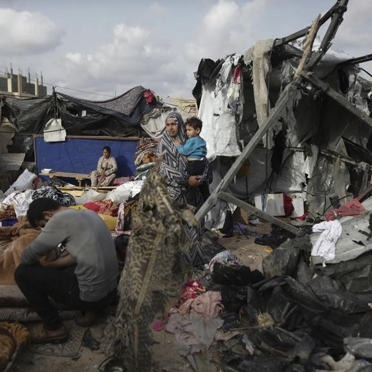 People in Gaza sit in the ruins of tents in which they were living.