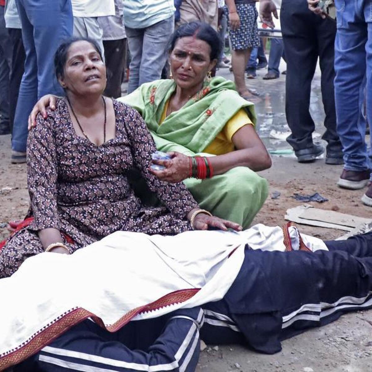 Women mourn next to the body of a relative in India