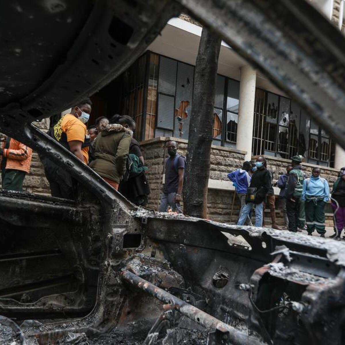 People walk past a car torched in Nairobi
