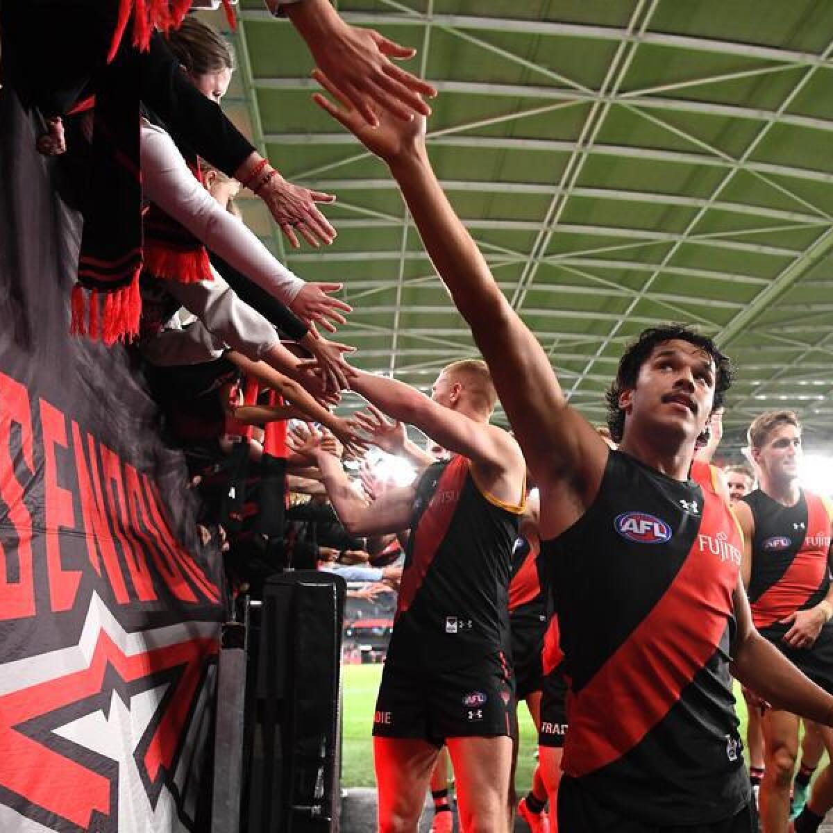 Essendon players celebrate with fans. 