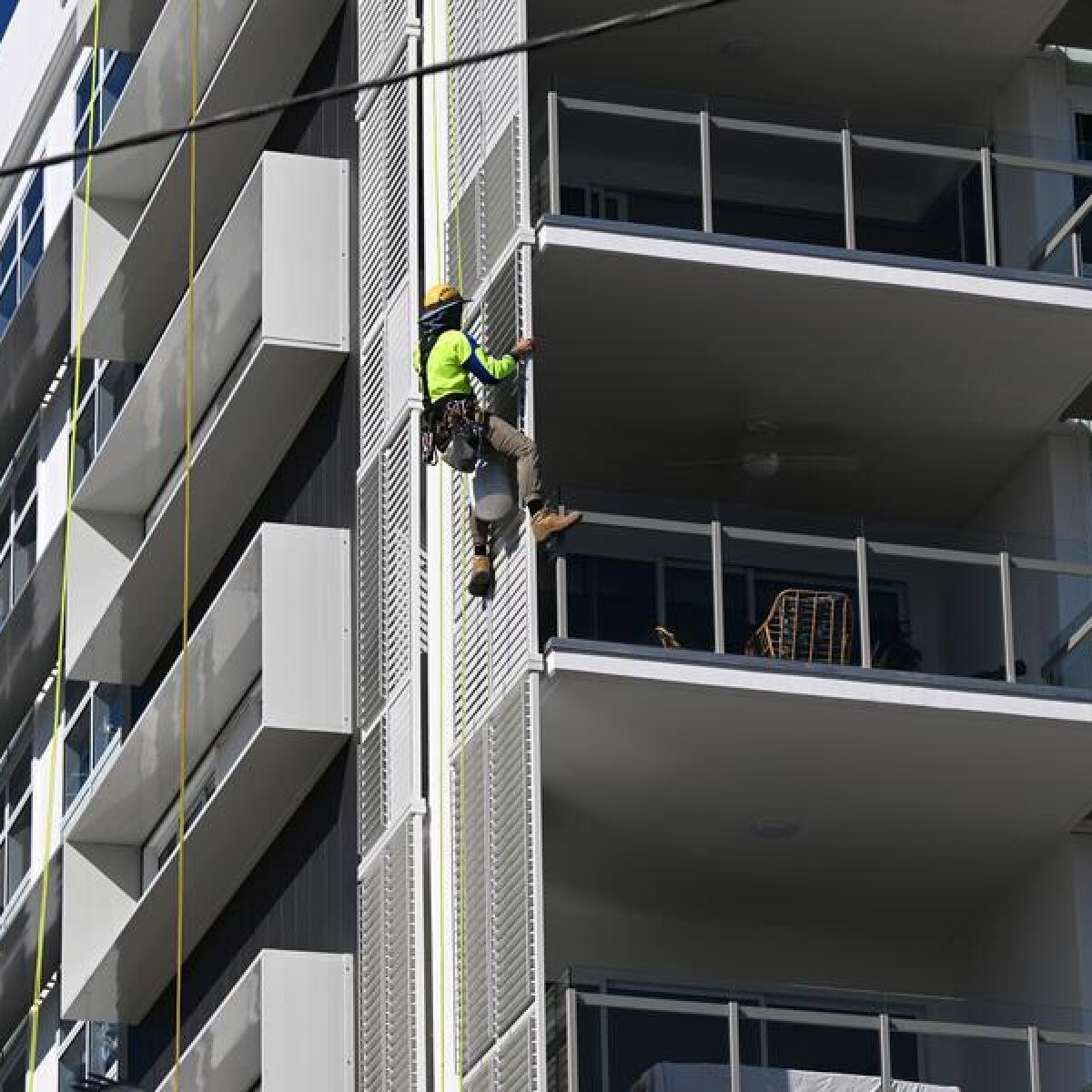 A construction worker is seen working on the side of a new apartment