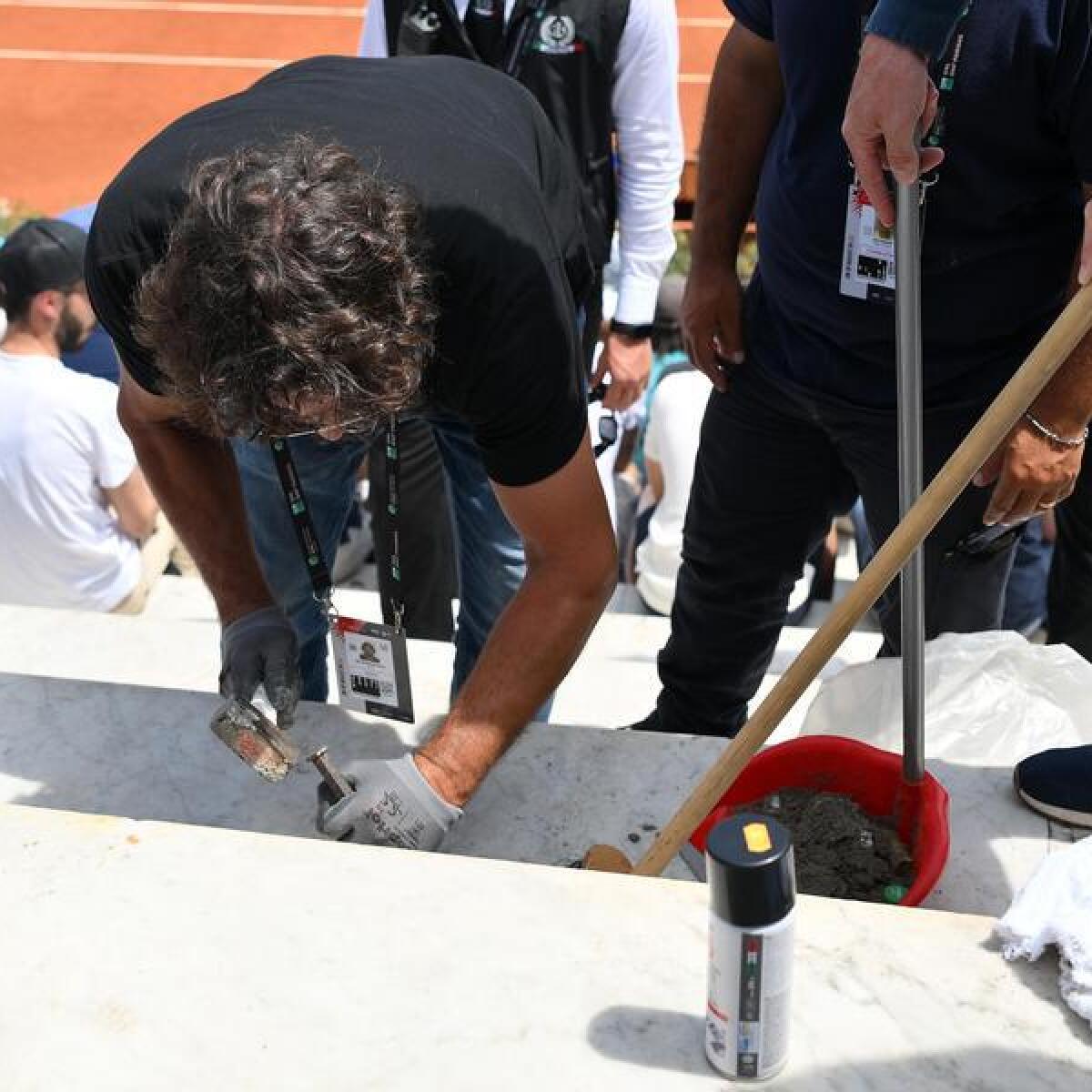 Italian Open staff remove cement from the seating.