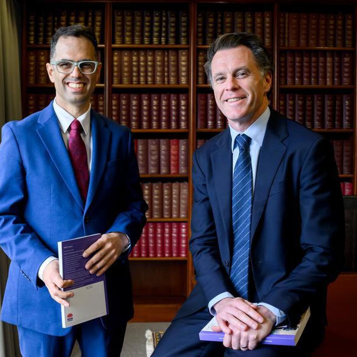The NSW treasurer and premier stand in front of a bookshelf.
