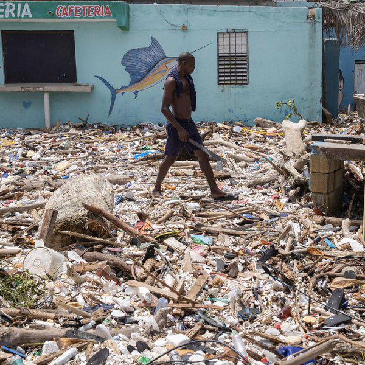 A man walks on a beach covered with garbage in the Dominican Republic