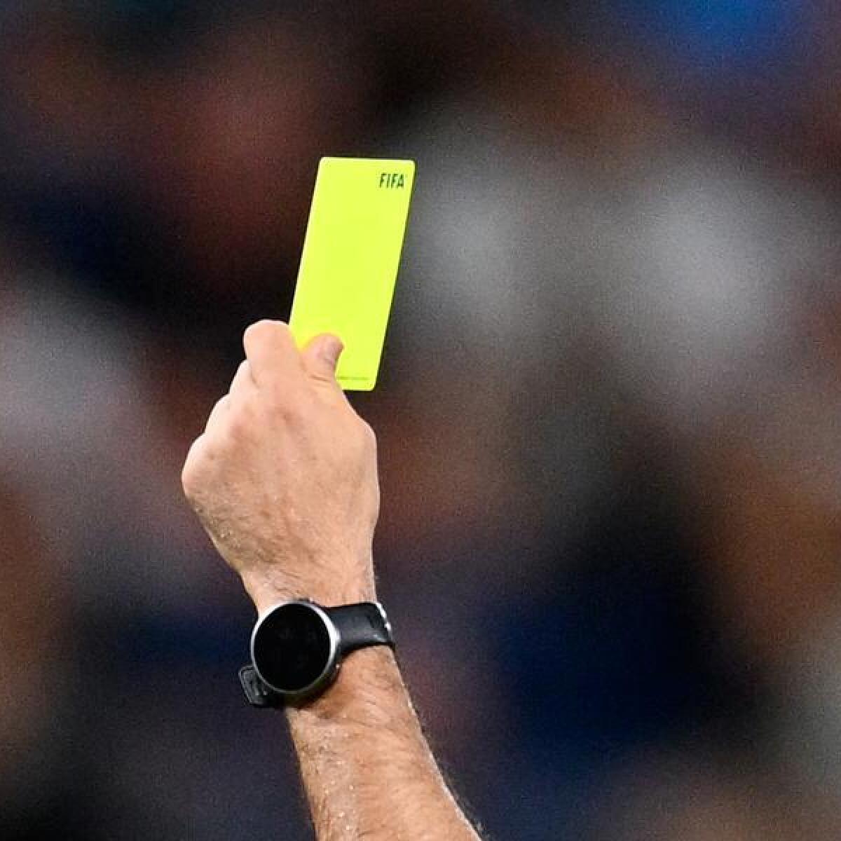 A referee holds a yellow card at a match not related to the arrests.
