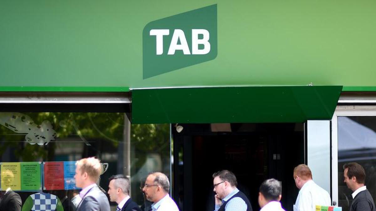 Men are seen walking past a TAB betting branch