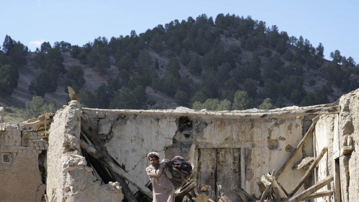 A man picks up belongings after the earthquake in Afghanistan.