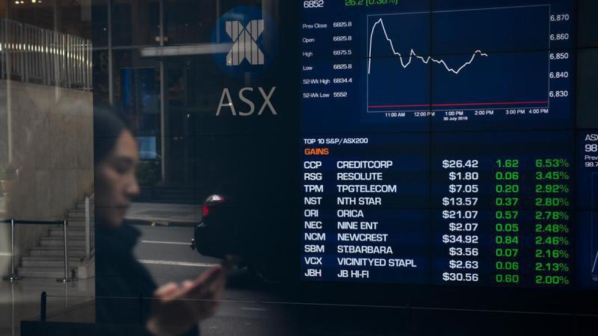 A woman on a city street; ASX trading display.