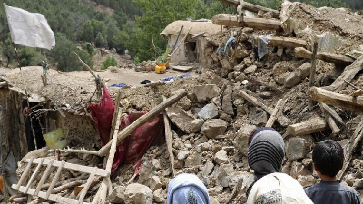 Children by a house destroyed in a quake in Afghanistan.