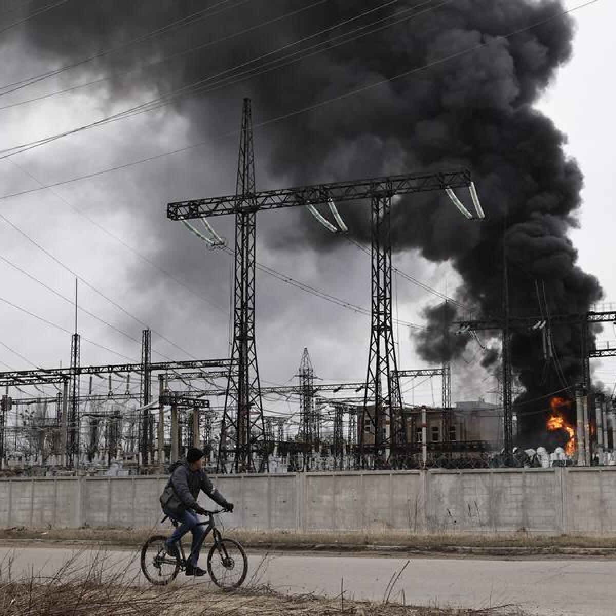 Man cycles past electrical facility after a Russian attack in Kharkiv.