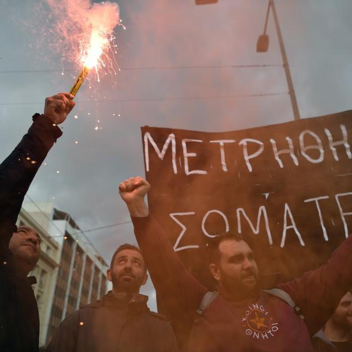 A protester holds a smoke flare during a rally in Athens, Greece