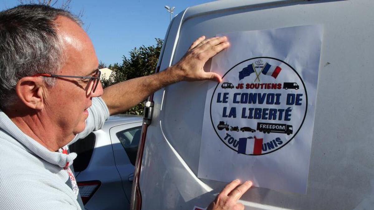 Man puts a "Liberty Convoy" poster on a lorry in Paris