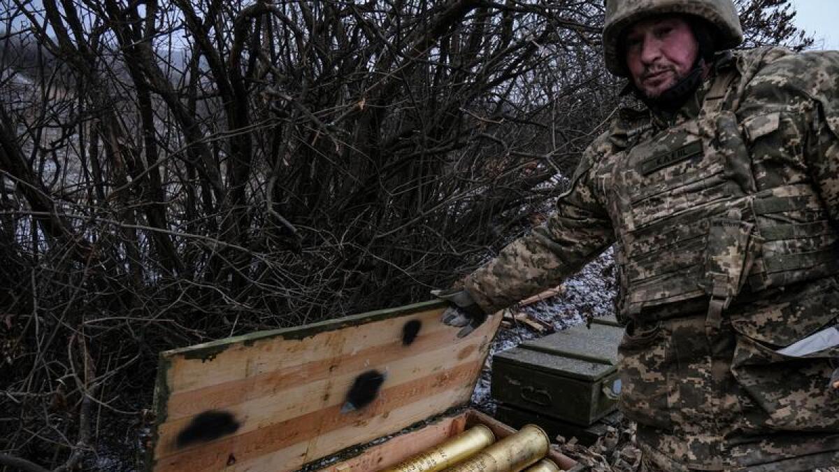 Ukrainian soldier shows a crate with artillery shells