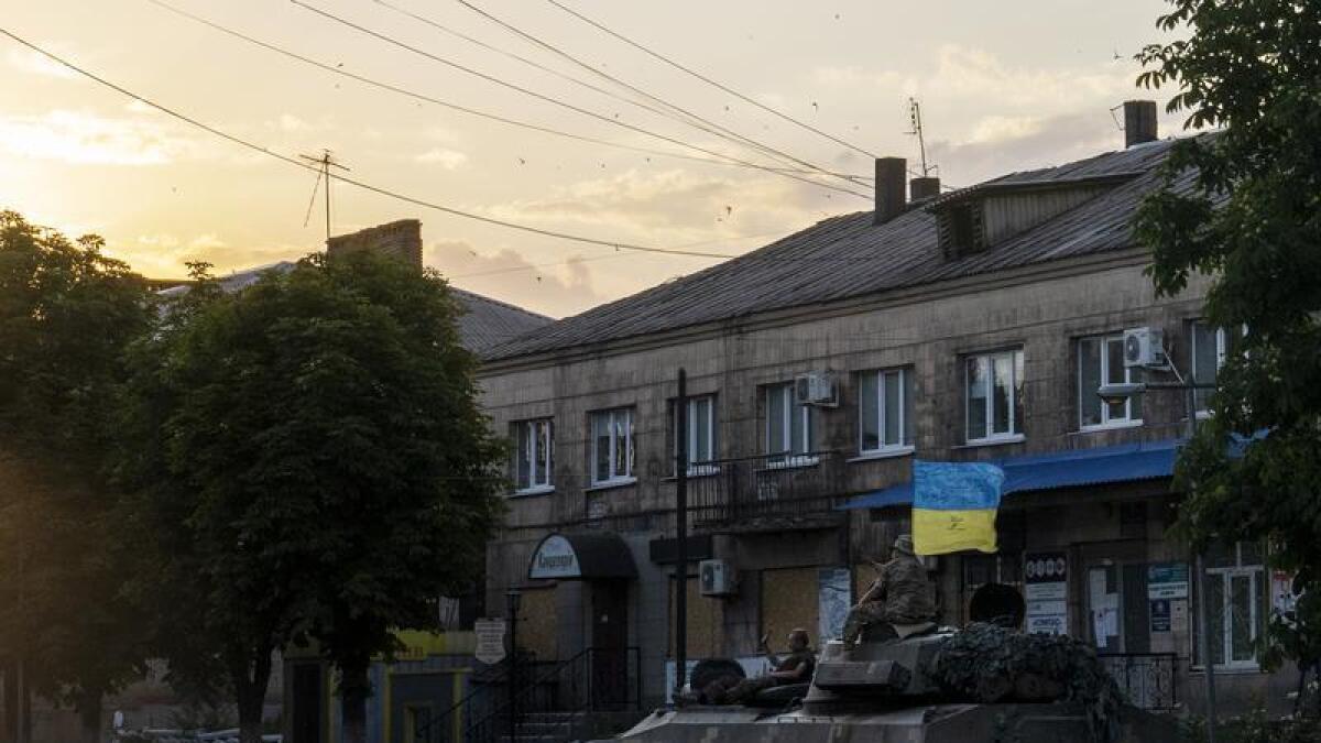 Ukrainian soldiers ride atop a tank in Donetsk