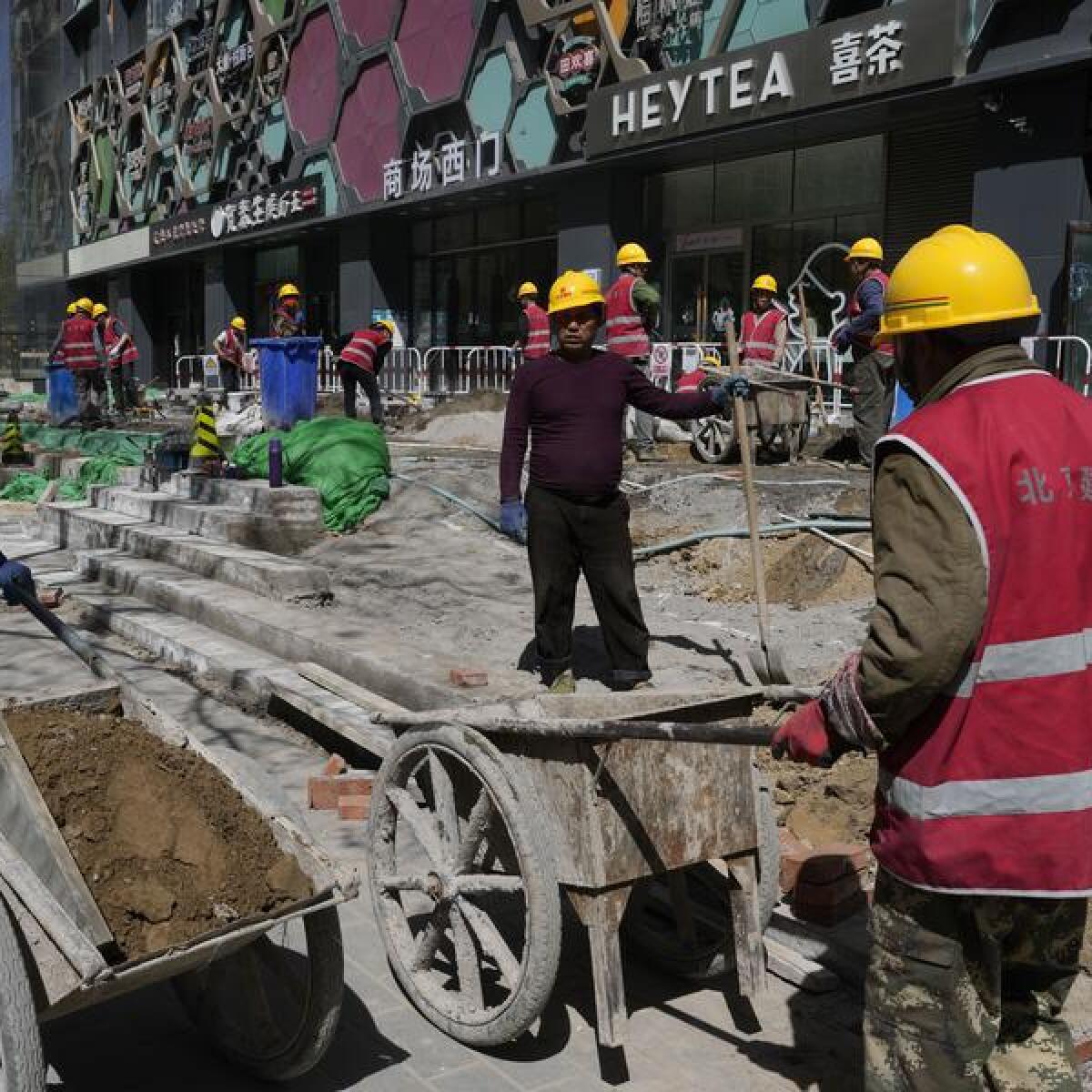 Workers renovate a walkway in front of a building in Beijing