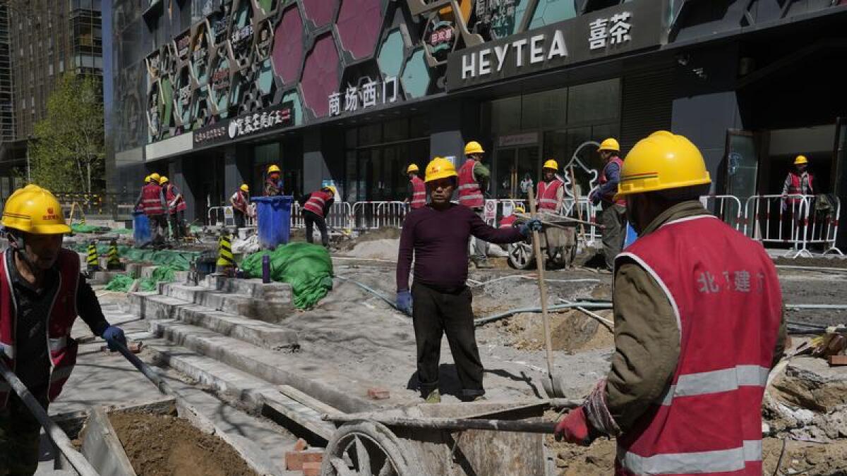 Workers renovate a walkway in front of a building in Beijing