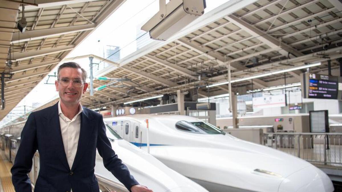 NSW Premier Dominic Perrottet alongside a bullet train in Tokyo.
