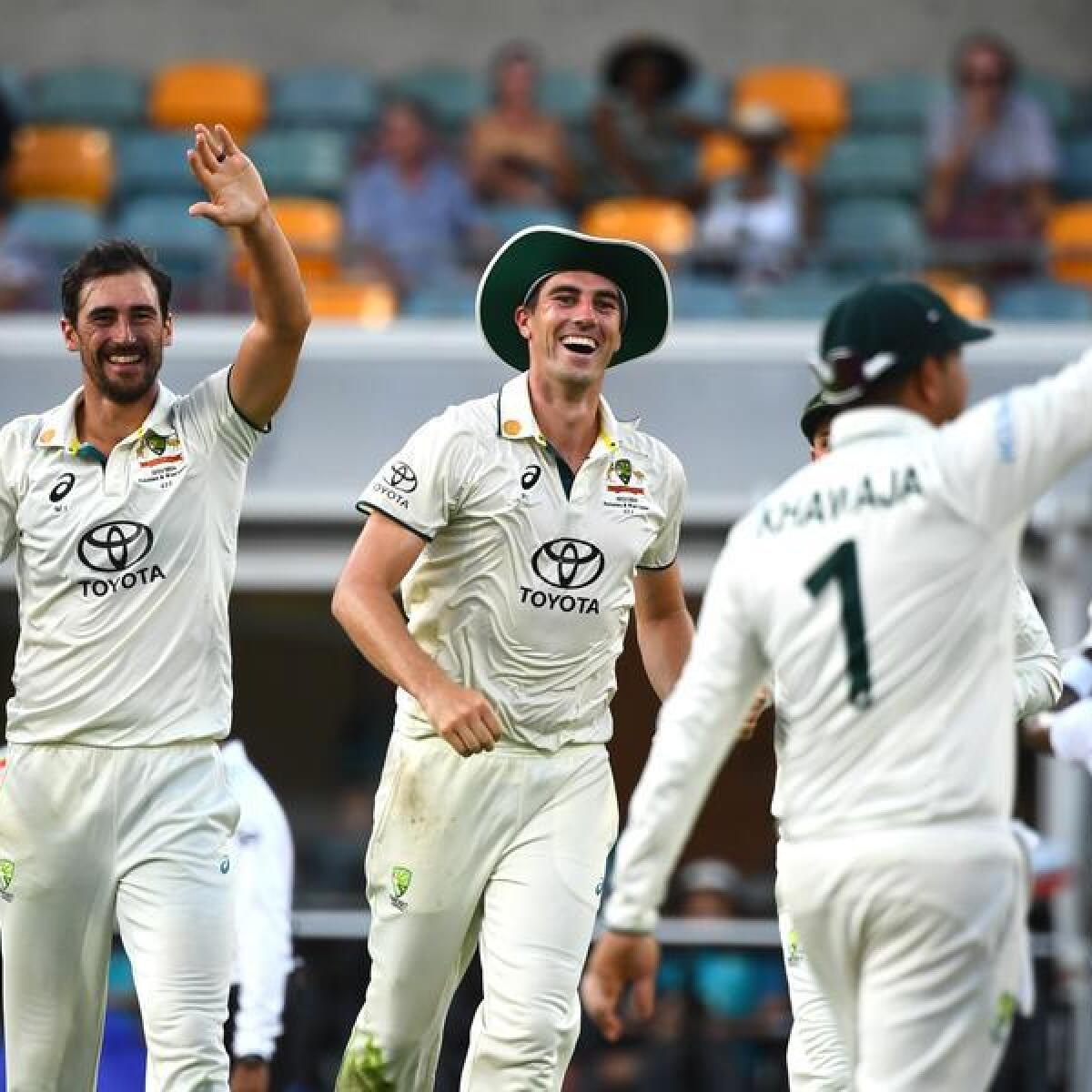 Pat Cummins and fellow Australian players celebrate a wicket.