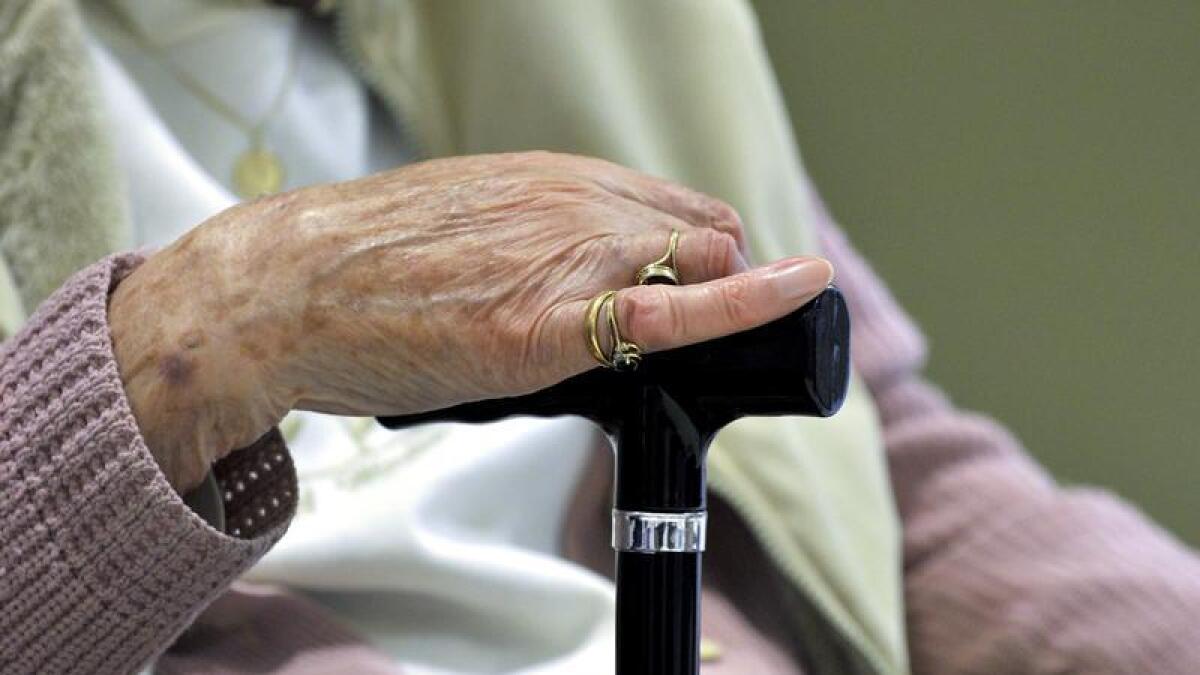 An elderly woman's hand on a walking stick