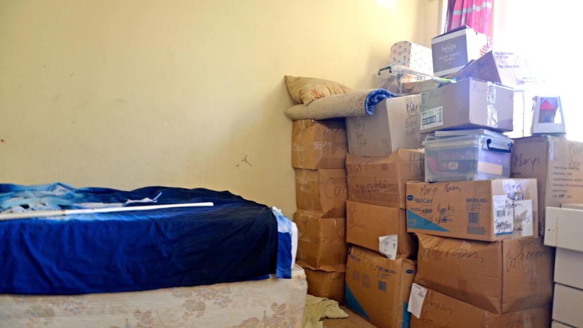 A bed with a pile of cardboard boxes next to it.